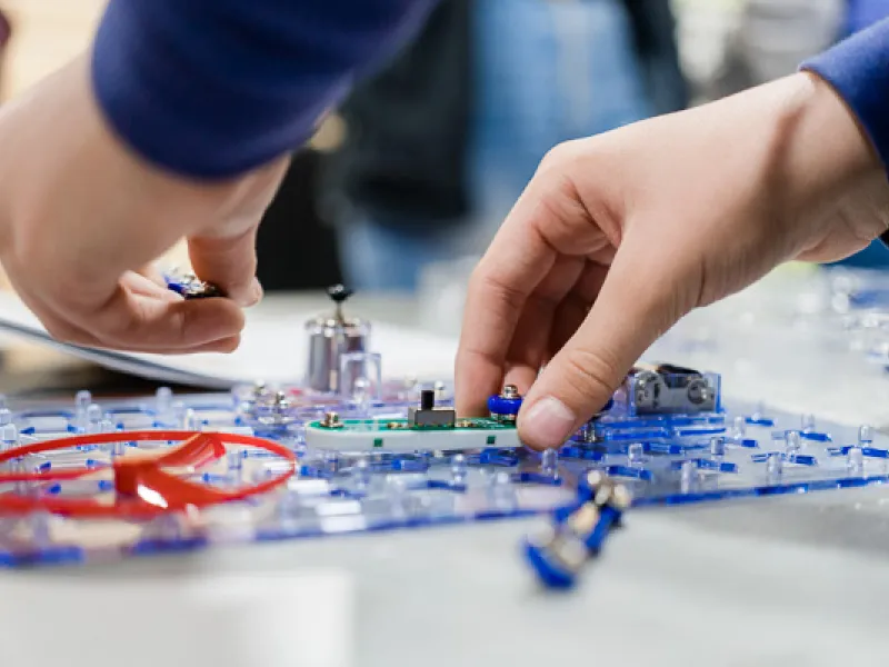 A close up photo of hands working with a circuit activity