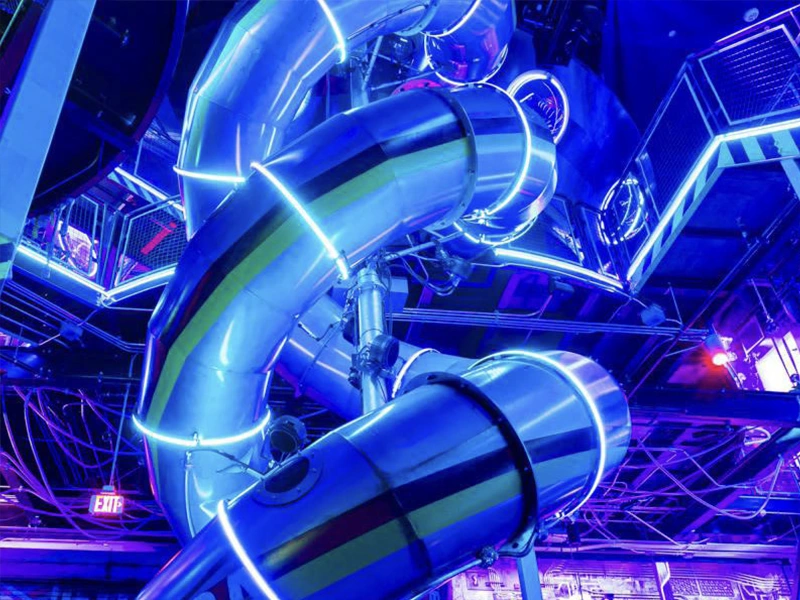 Metalic swirling spiral slide. Neon blue and purple lights reflecting on the room and the slide.