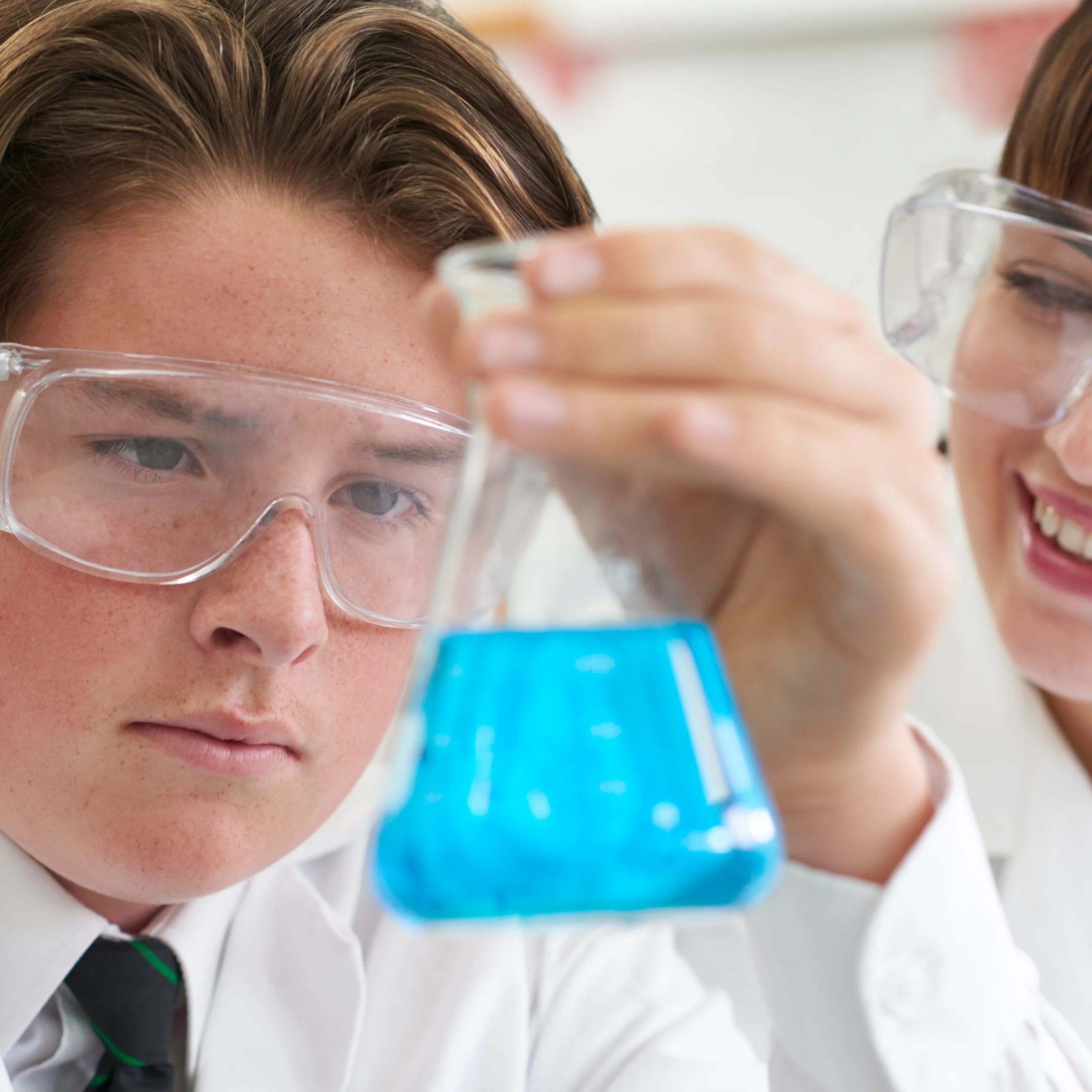 Boy and woman looking at blue liquid in a lab